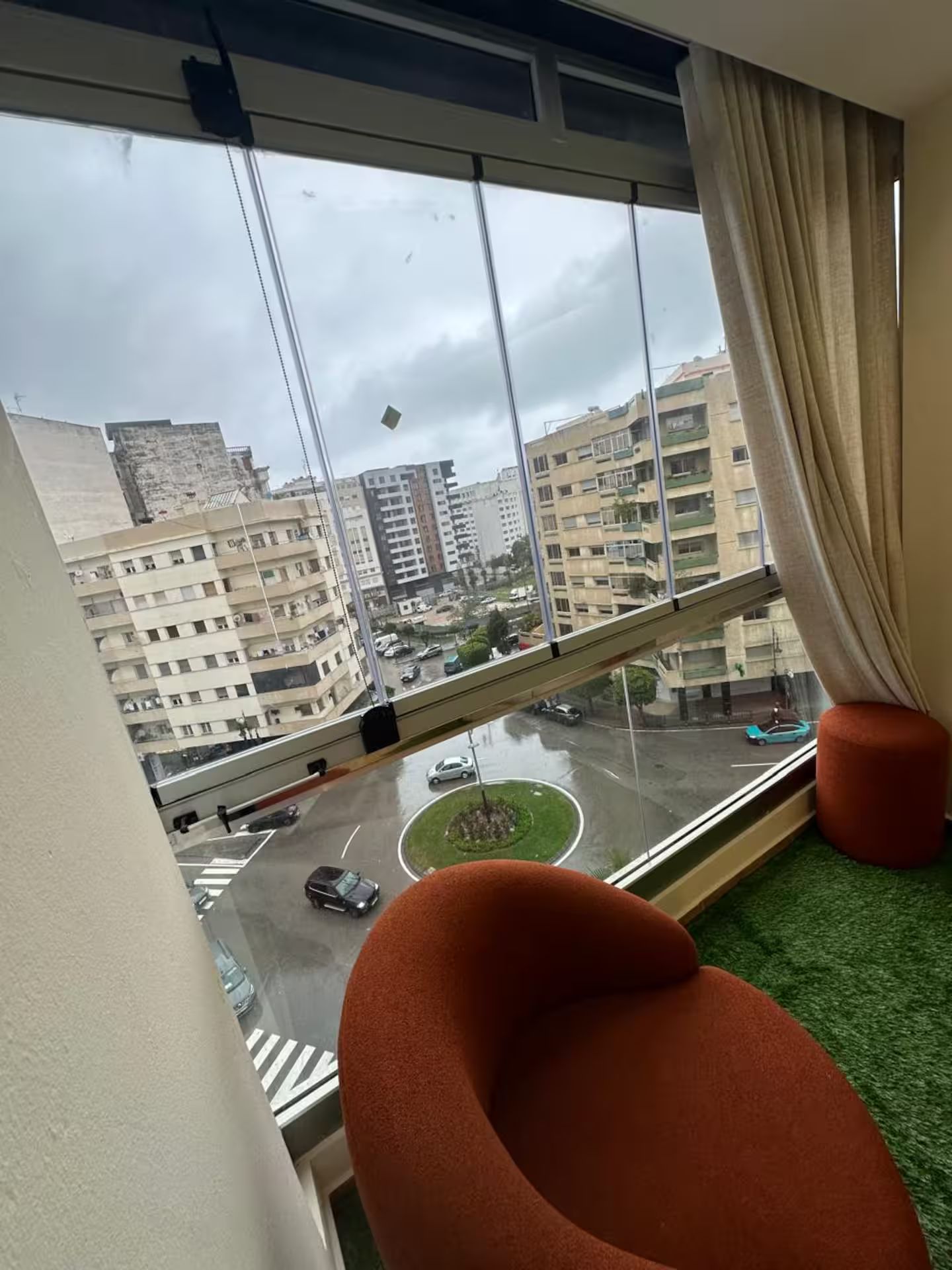 Une pièce dotée d’une grande fenêtre donnant sur un paysage urbain, un carrefour giratoire et un pont.