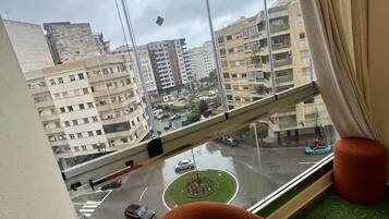 Une pièce dotée d’une grande fenêtre donnant sur un paysage urbain, un carrefour giratoire et un pont.