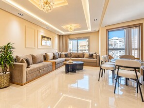 Ein modernes Wohnzimmer mit einer Eckcouch, einem runden Couchtisch und einem Essbereich mit Stühlen.