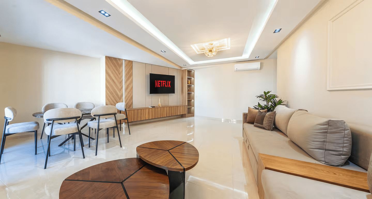 Un salon moderne doté d’un téléviseur à écran plat, d’un coin repas avec des chaises, d’un canapé et d’une table basse.