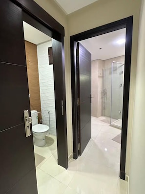 A modern bathroom with a toilet, a shower, and a glass-enclosed shower area. - Experience Modernity Beachside & Parking in Pleasant 2-bedroom apartment with AC (Tangier)