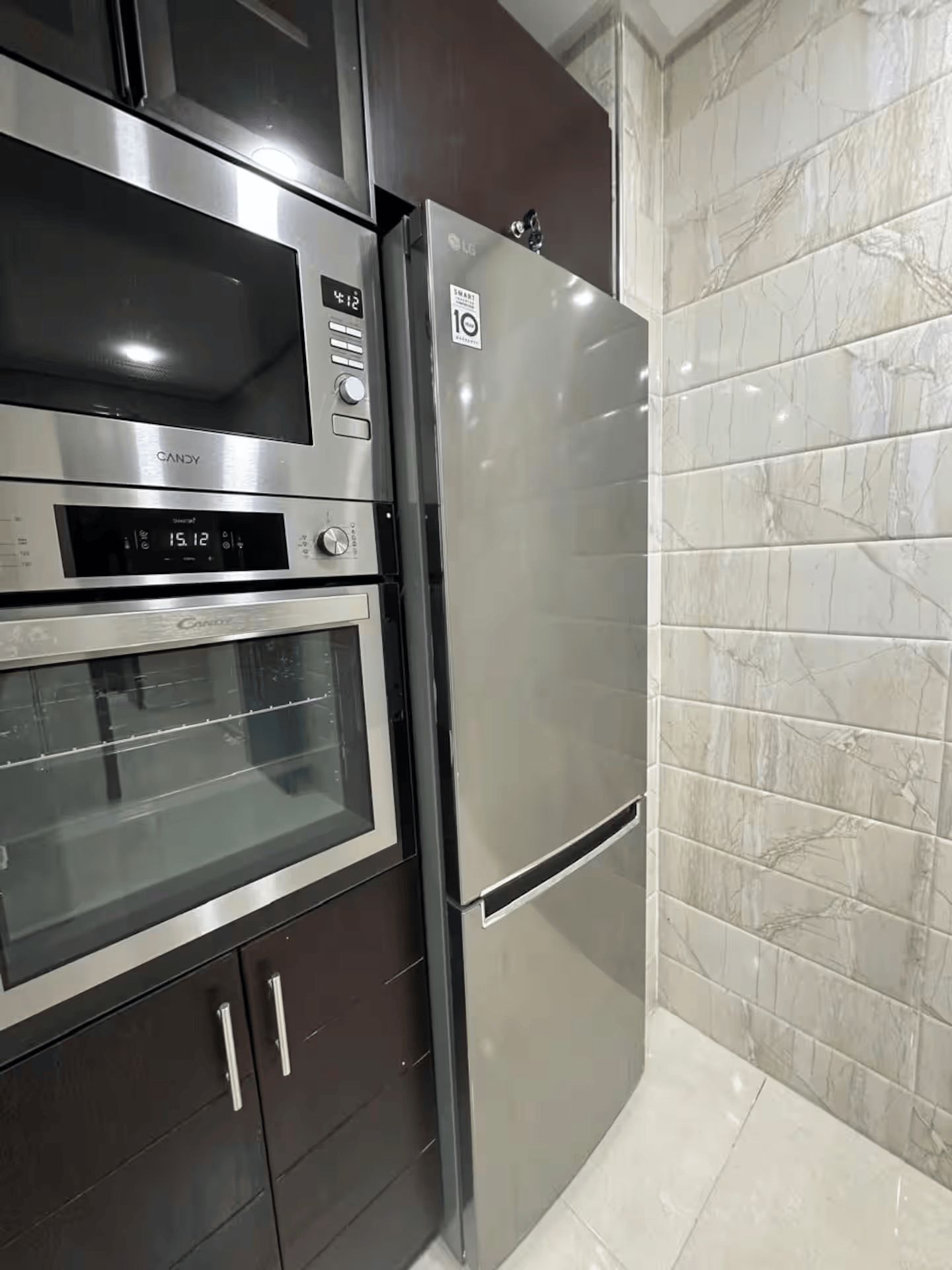 Eine Küche mit einem Edelstahl-Kühlschrank, Backofen und einer Mikrowelle.