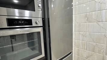 Eine Küche mit einem Edelstahl-Kühlschrank, Backofen und einer Mikrowelle.
