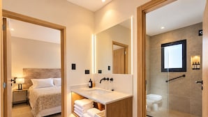 A modern hotel bathroom with a large mirror, a sink, and a shower area.