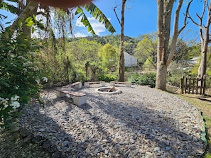 A garden with a circular seating area surrounded by pebbles and trees.
