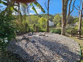 Un jardín con una zona de estar circular, rodeada de piedras y árboles.