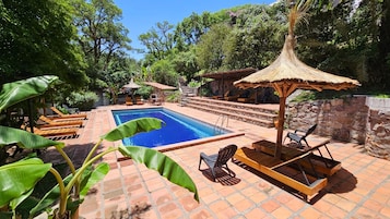 Una piscina al aire libre, sillones reclinables de piscina