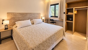 A hotel room with a large bed, bedside tables with lamps, a desk, and a wardrobe.