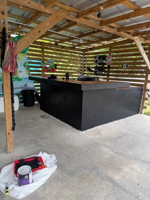 Eine Holzhütte mit einer schwarzen Theke, einer Strandmalerei und einem Schild, das eine Bar anzeigt.
