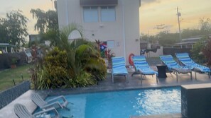 Ein Poolbereich mit Liegestühlen und einem Gebäude im Hintergrund.
