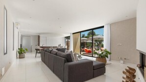 A modern living room with a large sectional sofa, a dining area, and a kitchen in the background. - La Villa Monarque  (Agde)