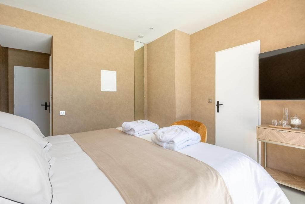 Una habitación de hotel con una cama, una silla, un escritorio con espejo y un televisor.
