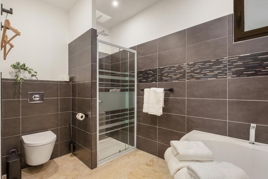 Ein modernes Badezimmer mit einer Duschkabine, einer weißen Toilette und einer Badewanne.
