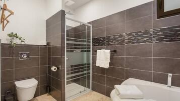 Ein modernes Badezimmer mit einer Duschkabine, einer weißen Toilette und einer Badewanne.