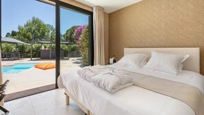 A bedroom with a large bed, a view of an outdoor swimming pool, and a glass door leading outside. - La Villa Monarque  (Agde)