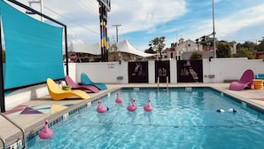 Piscina com flamingos infláveis e cadeiras de sol coloridas.