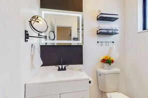 A bathroom with a white sink, a mirror, a toilet, and a towel rack. - Serene 1-bedroom suite, boutique hotel in Albuquerque (Albuquerque)