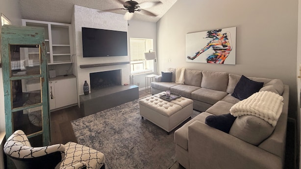 Ein Wohnzimmer mit Kamin, Fernseher, Deckenventilator und einer Couch.