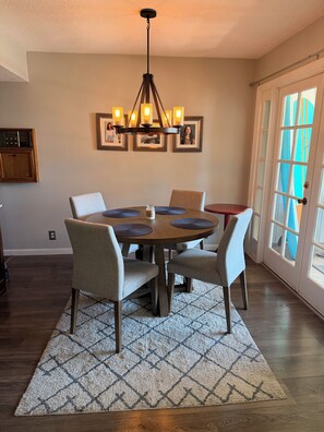 A dining area with a chandelier, framed pictures, and a view through a glass door. - Vaulted ceilings, brand new appliances, overlooking pool/hot tub of complex. (Scottsdale)
