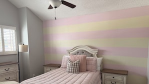 Ein Schlafzimmer mit einem Bett, Nachttischen, einer Lampe und einem Deckenventilator.