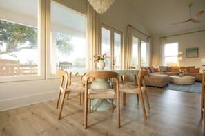 Amplia sala de estar con una gran mesa de comedor, múltiples sillas, un sofá y un ventilador de techo.