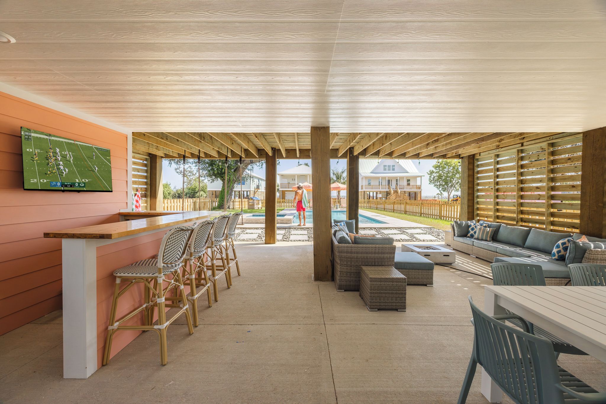 A covered outdoor area with a bar, seating, and a pool.
