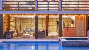 A two-story building with a pool, outdoor seating, and a wooden deck.