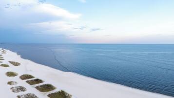 Eine Küstenlandschaft mit weißen Sanddünen und ruhiger See.