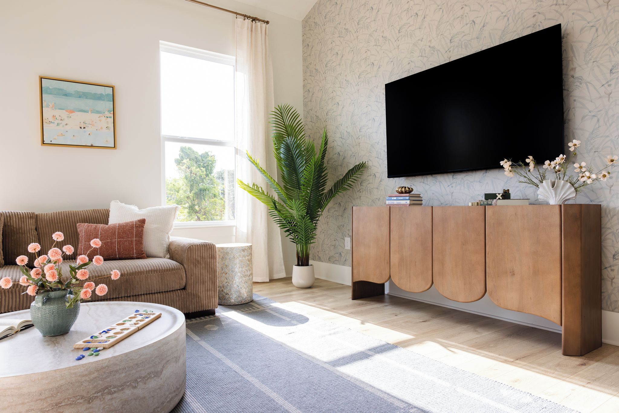 Ein Wohnzimmer mit einer Couch, einem Couchtisch mit einem Gesellschaftsspiel, einem Blumentopf, einem Fernseher und einem Bücherregal.