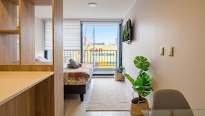Quarto moderno com cama, escrivaninha e uma grande janela.