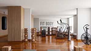 Uma academia moderna com um saco de pancada, kettlebells, uma bicicleta ergométrica e uma esteira.