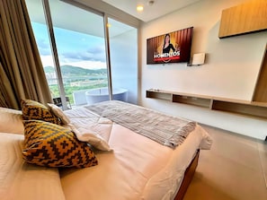 Een hotelkamer met een bed, een aan de muur bevestigde televisie en uitzicht op het omliggende landschap.