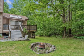 A house with a deck, a fire pit, and a backyard. - Quechee Art and Trail Retreat (Quechee)