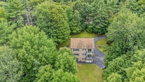 A two-story house surrounded by dense green trees. - Quechee Art and Trail Retreat (Quechee)
