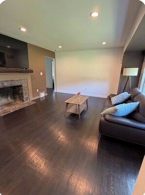 A living room with a fireplace, a sofa, a coffee table, and recessed ceiling lights.
