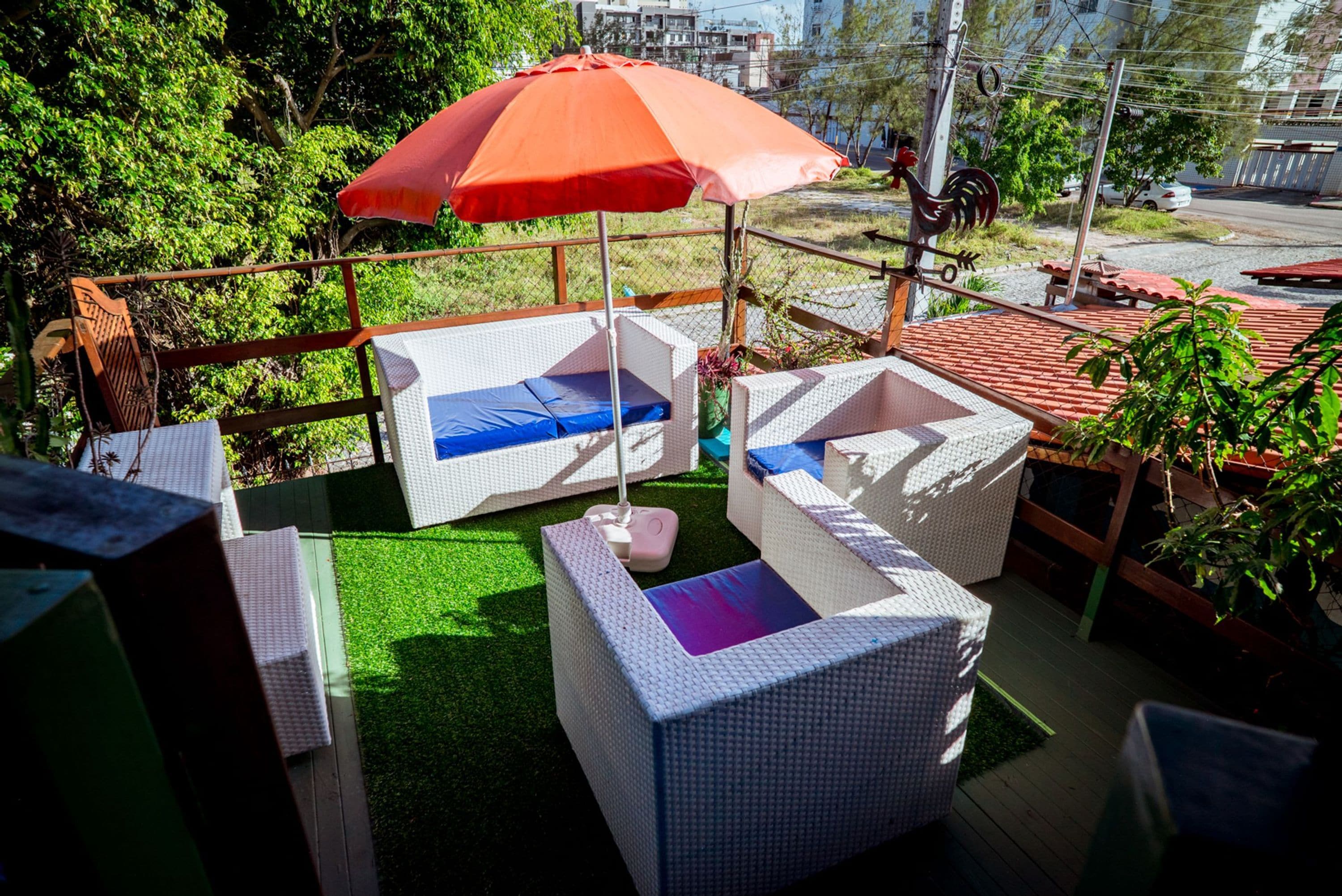 An outdoor seating area with wicker furniture and a red umbrella.