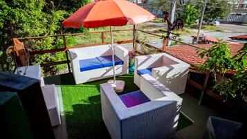 An outdoor seating area with wicker furniture and a red umbrella.