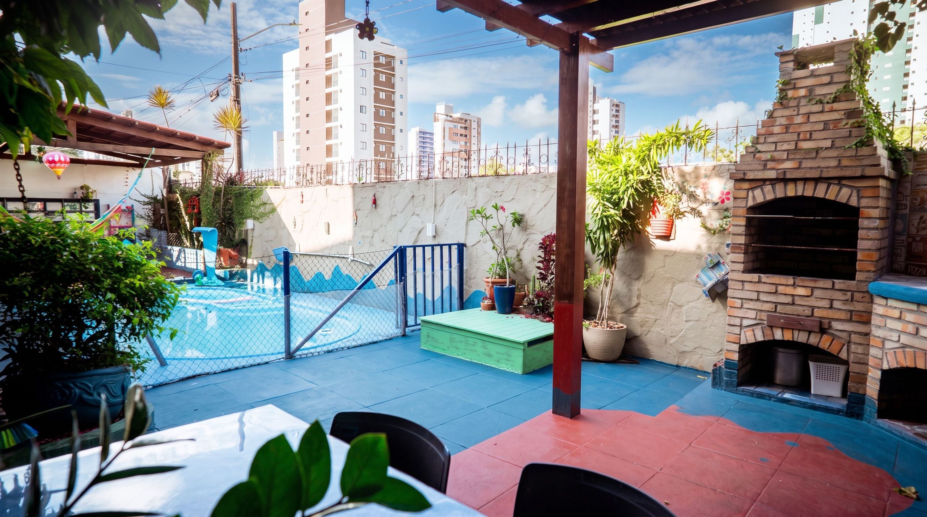 An outdoor patio with a pool, a brick oven, and potted plants.