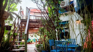 A narrow outdoor pathway leading to a seating area with blue chairs and potted plants. - Casa com Piscina e Churrasqueira em Jardim Oceania (João Pessoa)