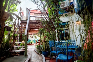 A narrow outdoor pathway leading to a seating area with blue chairs and potted plants. - Casa com Piscina e Churrasqueira em Jardim Oceania (João Pessoa)