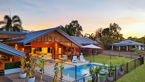 A residential property with a swimming pool, outdoor seating area, and a covered patio.