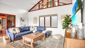 A modern living room with a blue leather sofa, wooden coffee table, and a large flat-screen TV.