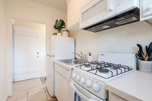 Eine kleine Küche mit einem Gaskochfeld, einem Spülbecken und einem Kühlschrank.