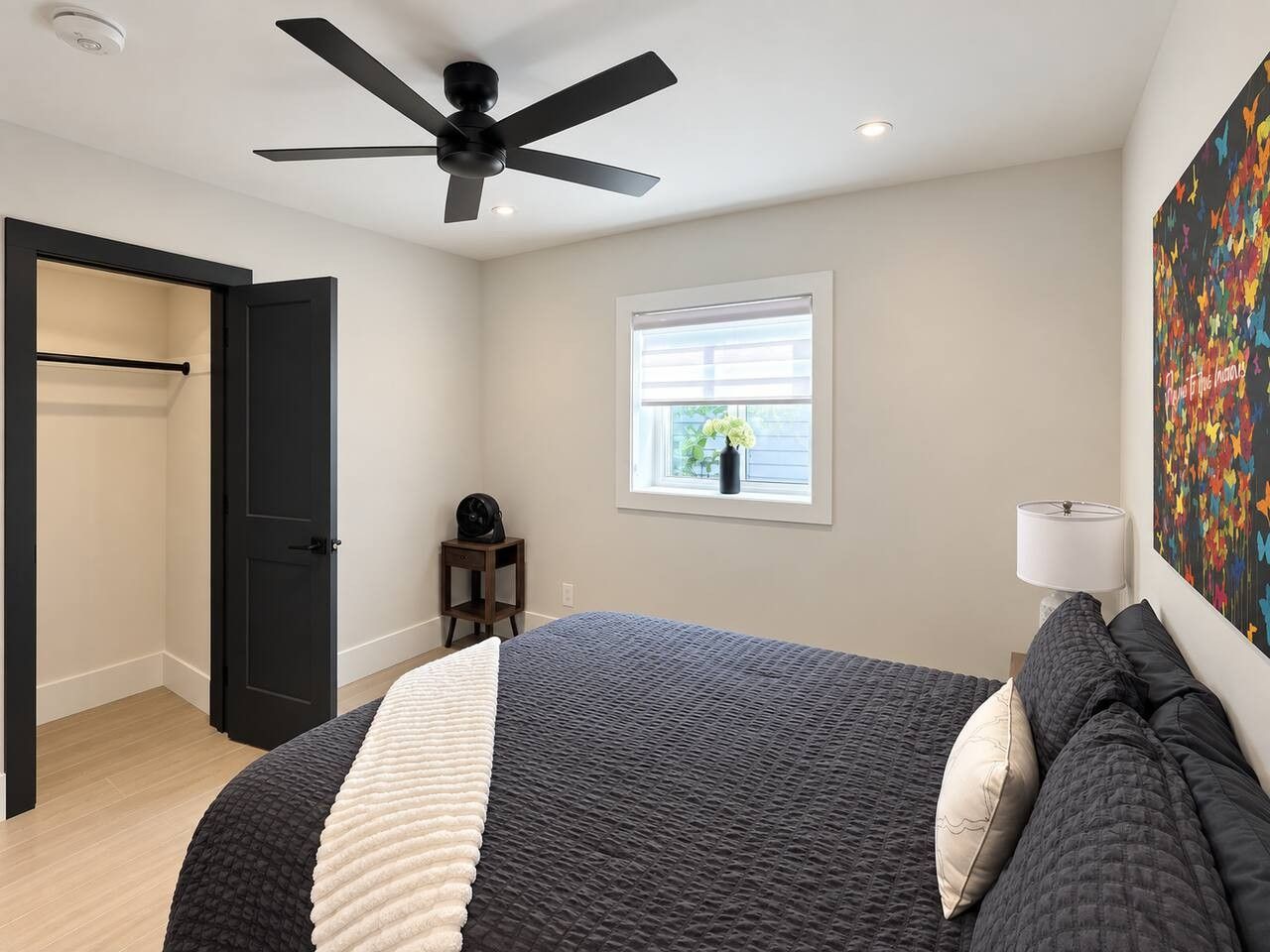 Une chambre à coucher avec un lit, un ventilateur de plafond, une fenêtre donnant sur un beau paysage et une porte.