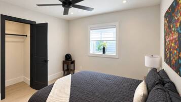 Une chambre à coucher avec un lit, un ventilateur de plafond, une fenêtre donnant sur un beau paysage et une porte.