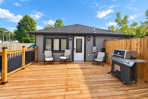 Une terrasse avec un barbecue et deux chaises.