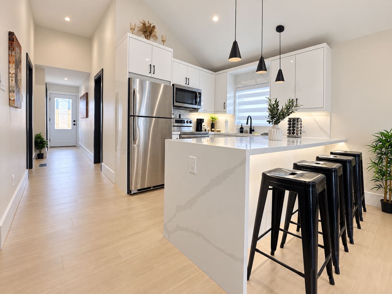 A modern kitchen with stainless steel appliances, a central island with bar stools, and pendant lighting.