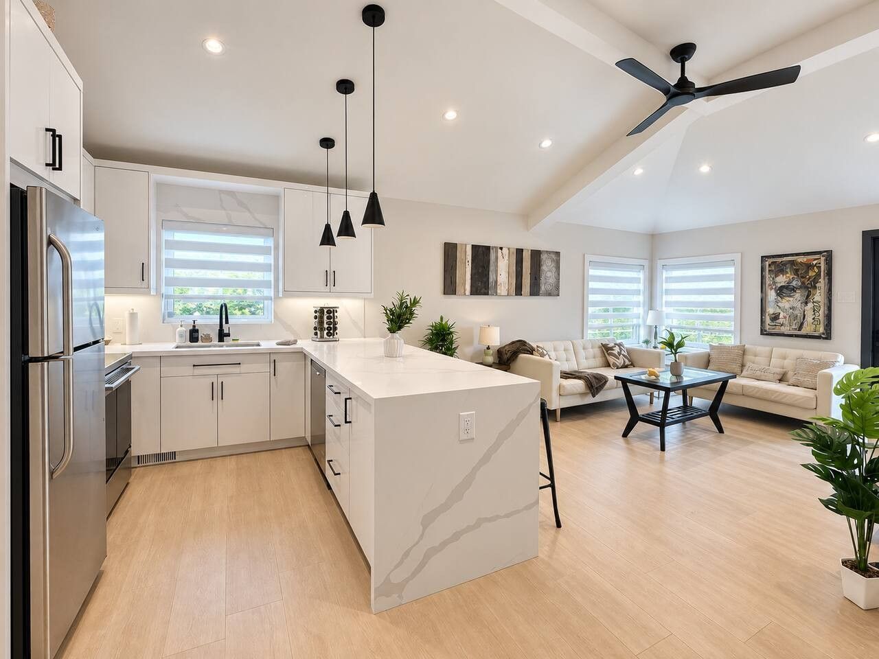 A modern kitchen with a central island, built-in appliances, pendant lighting, and a ceiling fan.