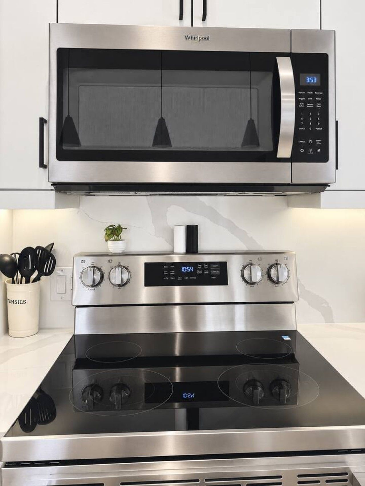 A kitchen with a stainless steel microwave above a stove with a digital display.