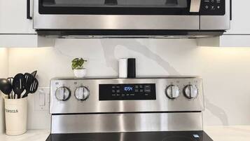 A kitchen with a stainless steel microwave above a stove with a digital display.